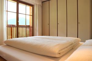 1 dormitorio con 1 cama blanca grande y ventana en Ciasa Cir Apartments, en Badia