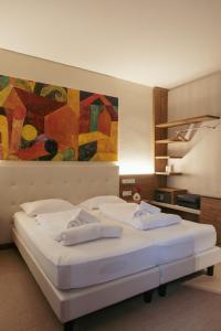 two beds in a room with a painting on the wall at Hotel Morgana in Mendrisio