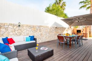 eine Terrasse mit einem Sofa, einem Tisch und einem Sonnenschirm in der Unterkunft Villa Dalia by Algarve Vacation in Almancil