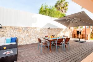 eine Terrasse mit einem Tisch, Stühlen und einem Sonnenschirm in der Unterkunft Villa Dalia by Algarve Vacation in Almancil