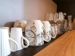 a row of mugs sitting on a table with glasses at Aparthotel AMMI Vieux Nice in Nice