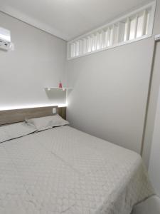 um quarto com uma cama branca e uma janela em Apartamento Pé na Areia em Florianópolis