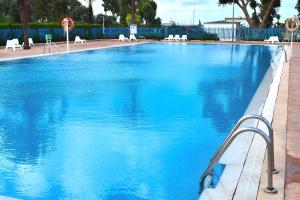 una gran piscina azul con mesas y sillas blancas en Coqueta casita de 2 habitaciones, en La Manga del Mar Menor
