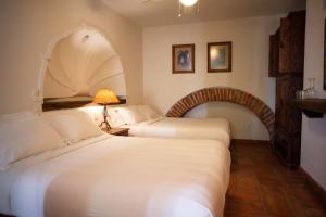 two beds in a hotel room with a arch at El Alcazar in San Miguel de Allende