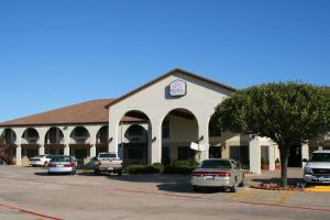 a large building with cars parked in a parking lot at Weatherford Heritage Inn in Weatherford