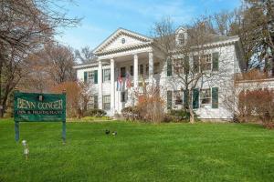 une grande maison blanche avec un panneau devant elle dans l'établissement Benn Conger Inn, à Groton