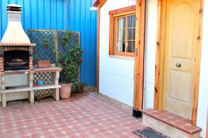un porche con chimenea junto a una casa azul en Coqueta casita de 2 habitaciones, en La Manga del Mar Menor