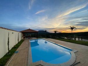 a swimming pool in a backyard with a sunset at Rancho Chega Mais 2 in Carmo do Rio Claro