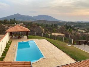 a pool with a gazebo next to a house at Rancho Chega Mais 2 in Carmo do Rio Claro