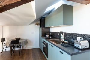 a kitchen with blue cabinets and a small table at Là-Haut - 3 Panorama of the Estuary - City Center in Honfleur