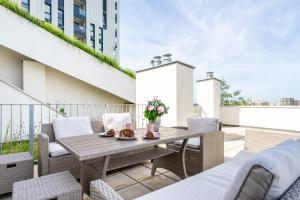 patio con mesa de madera y sillas en el balcón en FeelGood Apartments GreenLiving | contactless check-in, en Viena