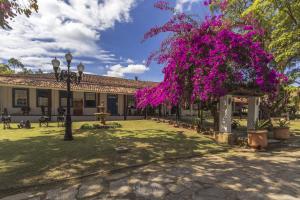 a building with a tree with purple flowers at Resort Fazenda 3 Pinheiros in Engenheiro Passos