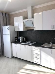 a kitchen with white cabinets and a white refrigerator at Уютная квартира с новым ремонтом in Leninskoye