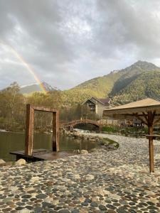 ein Regenbogen am Himmel über einem Fluss mit einer Brücke in der Unterkunft Yetihouse in Teberda