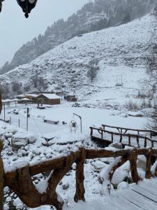 ein schneebedecktes Feld mit Spielplatz im Hintergrund in der Unterkunft Yetihouse in Teberda
