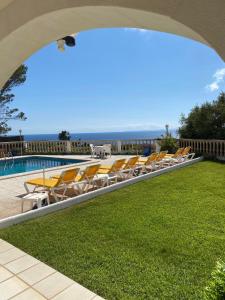 a pool with chairs and the ocean in the background at Villa Can Pere Cala Galdana Menorca in Cala Galdana