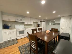 a kitchen with white cabinets and a wooden table with chairs at Salt Lake City Sweet Spot in Murray