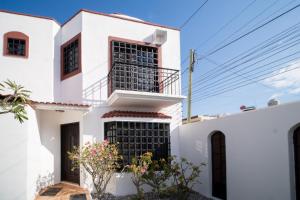 une maison blanche avec des fenêtres noires dans l'établissement PENINSULA STAYS 3 BR House & AC + Private Parking + FAST WIFI, à Chetumal