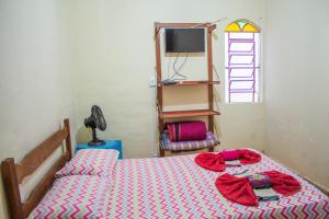 a bedroom with a bed with red sheets and a television at Pousada da Mica in Carrancas