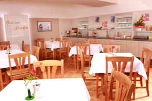 Un comedor con mesas blancas y sillas de madera. en Hotel & Gasthof zum Rödelseer Schwan, en Rödelsee