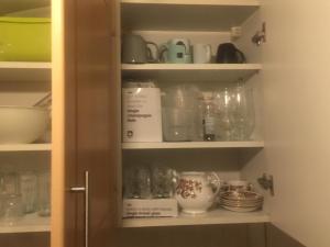 a cupboard filled with dishes and other kitchen items at DACH Apartments - Cozy 3 bed Apartment in Hendon in Colindale