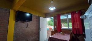 Una sala de estar con una mesa y un televisor en la pared. en Departamentos Las Marias, en Villa Cura Brochero
