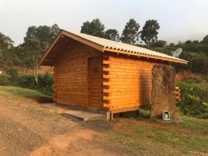 eine Holzhütte mit Baumstumpf daneben in der Unterkunft Cabana da Colina 2 in Bom Jardim da Serra