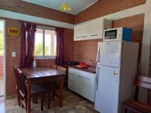 cocina con nevera blanca y mesa de madera en Departamentos Las Marias, en Villa Cura Brochero