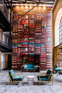 a large wall of books in a room with chairs at Hotel Perte at Montecasino in Johannesburg
