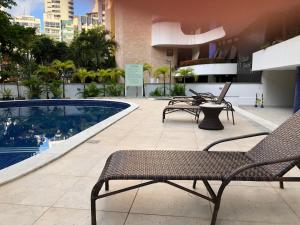 a patio with chairs and a pool on a building at Flat encantador no Atlantic Towers in Salvador