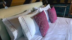 3 almohadas en una cama con almohadas rosas y blancas en Casas de Pedra en Camacha