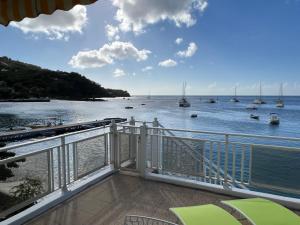 a balcony with a view of the water with boats at Ti Cabanon. Appartement vue mer à Deshaies. in Deshaies