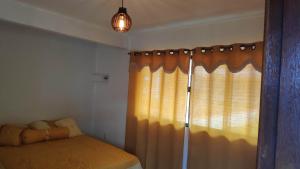 um quarto com uma cama e uma janela com cortinas em Flat com portão na Praia em Angra dos Reis