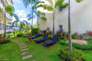 un cortile con sedie blu e palme e un edificio di KARON BUTTERFLY KATA HILL CONDO By THE SEA a Ban Karon Altre 35 foto