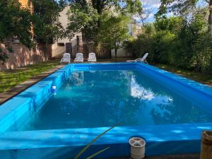 uma piscina azul com cadeiras num quintal em La Escondida Salta 2 em General Alvarado