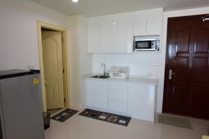 een witte keuken met een wastafel en een koelkast bij The Energy Seaside Huahin by PP in Ban Bo Khaem