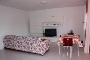 ein Wohnzimmer mit einem Sofa und einem TV in der Unterkunft Appartamento Greta in Porto Azzurro
