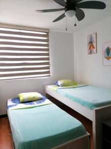 Habitación con 2 camas individuales y ventilador de techo. en Hospedaje eje cafetero, en Armenia
