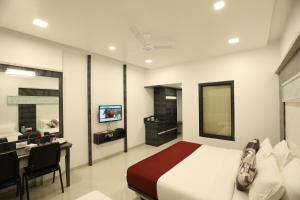 a bedroom with a bed and a desk and a television at Imperial Grande Resort in Lonavala
