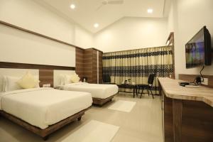 a hotel room with two beds and a flat screen tv at Imperial Grande Resort in Lonavala