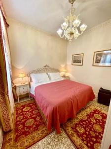 ヴェネツィアにあるSan Gregorio Venice Apartmentsのベッドルーム1室(赤い毛布とシャンデリア付きのベッド1台付)