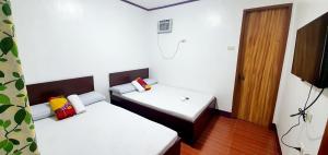 SJ Pabua Travellers Inn في مامباجاو: غرفة صغيرة بسريرين وباب