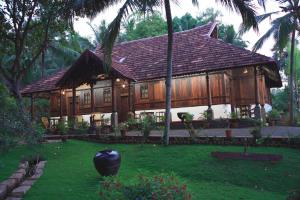 a large wooden house with a lush green yard at Somatheeram Ayurveda village in Kovalam