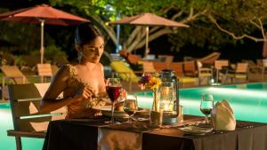 una donna seduta a un tavolo con un bicchiere di vino di Sooriya Resort & Spa a Tangalle