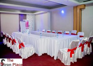 ein Zimmer mit weißen Tischen und Stühlen mit roten Bögen in der Unterkunft The Siron Place Hotel in Ongata Rongai 