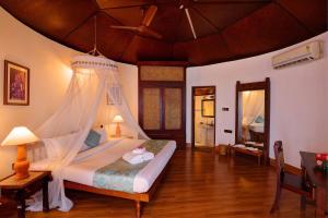 a bedroom with a bed with a mosquito net at Soma Manaltheeram Ayurveda BeachVillage in Kovalam +39 photos