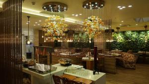 a restaurant with tables and chairs and chandeliers at De Glance Hotel in Surat