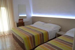 a hotel room with two beds and a window at Hotel Rosa Del Tirreno in Quercianella