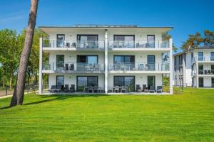 a large white building with a lawn in front of it at Appartement Inselzauber - Oase am Haff in Garz