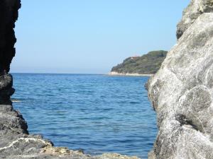 a view of the ocean from between two rocks at Hotel Rosa Del Tirreno in Quercianella